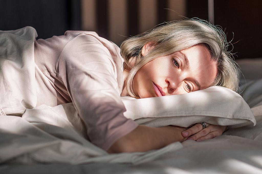 Pensive middle age woman lying in bed