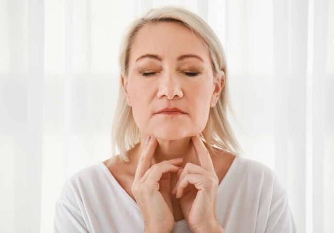 Woman checking her thyroid glas but may be menopause.