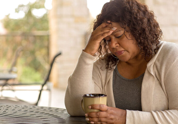 Middle aged Black women feeling exhausted with hand on head